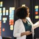 Uma equipe multidisciplinar de profissionais da saúde reunida em frente a um quadro Kanban, discutindo estratégias e melhorias nos processos hospitalares.