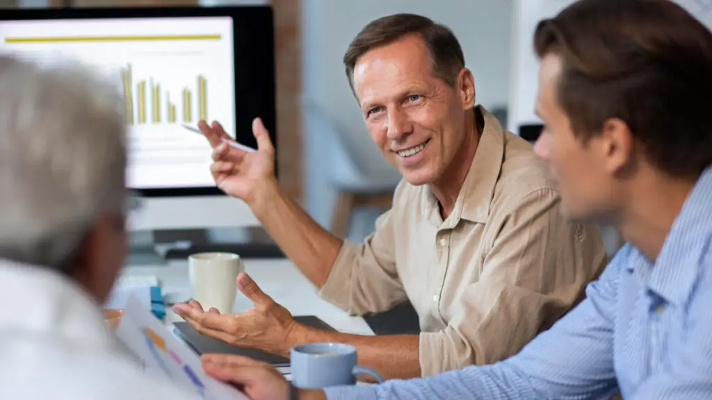 Reunião de equipe em um ambiente corporativo de saúde, com profissionais analisando dados e gráficos de programas de promoção e prevenção em saúde.