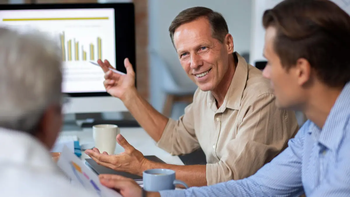 Reunião de equipe em um ambiente corporativo de saúde, com profissionais analisando dados e gráficos de programas de promoção e prevenção em saúde.