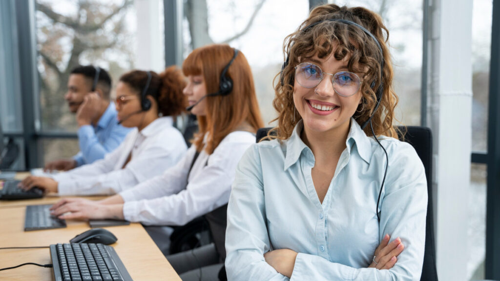Gestora de saúde com equipe de atendimento ao fundo em ambiente profissional e iluminado.